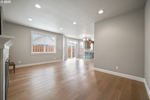3100 NE 171st St, Ridgefield, WA 98642 - unfurnished living room featuring a chandelier, a tile fireplace, light wood finished floors, recessed lighting, and a textured ceiling