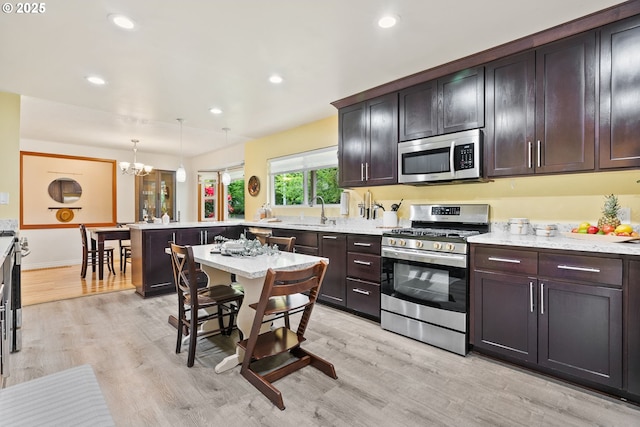 7005 SW 14th Ave, Portland, OR 97219 - kitchen featuring appliances with stainless steel finishes, a sink, a peninsula, a chandelier, and light wood-style floors