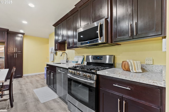 7005 SW 14th Ave, Portland, OR 97219 - kitchen with stainless steel appliances, a sink, light stone counters, light wood-type flooring, and dark brown cabinetry