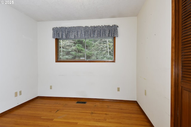 empty room with hardwood / wood-style floors and a textured ceiling