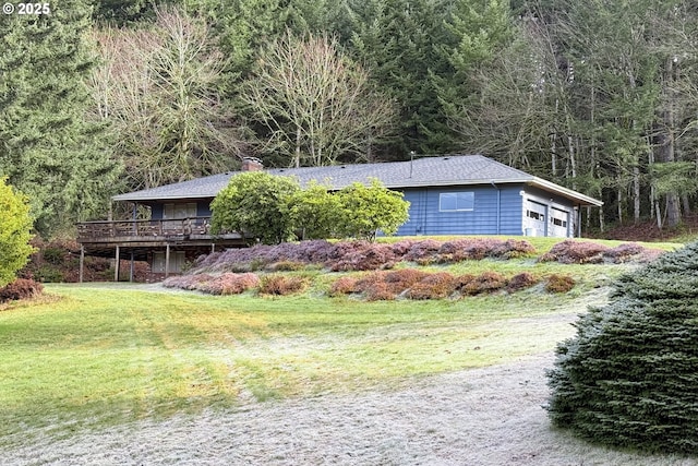 view of side of property with a wooden deck, a garage, and a yard