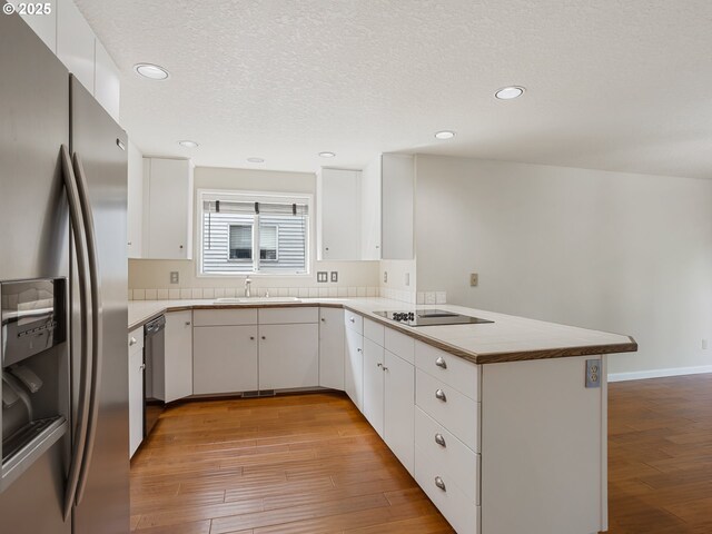 15917 NE Union Rd Unit 103, Ridgefield, WA 98642 - kitchen featuring stainless steel fridge, a peninsula, light wood-style floors, black electric cooktop, and dishwashing machine