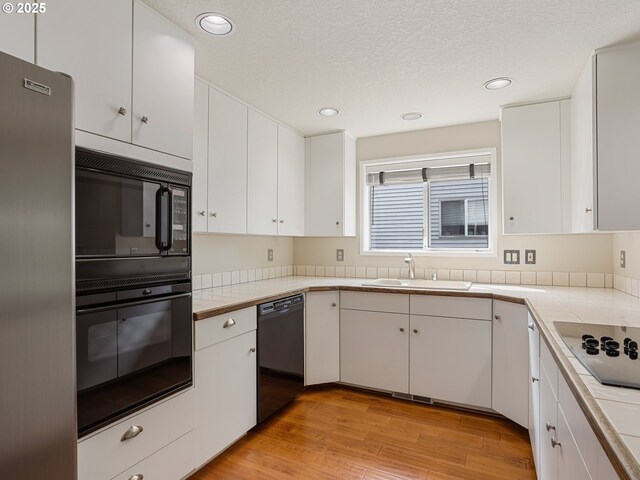 15917 NE Union Rd Unit 103, Ridgefield, WA 98642 - kitchen featuring black appliances, white cabinets, light wood-style flooring, recessed lighting, and tile countertops
