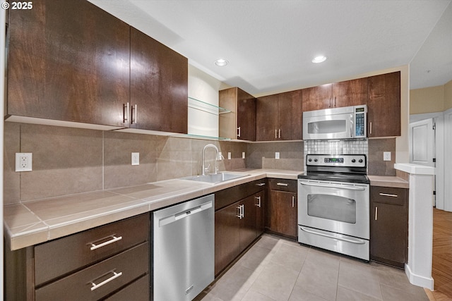 630 NE Adwick Dr, Hillsboro, OR 97006 - kitchen with appliances with stainless steel finishes, a sink, dark brown cabinets, tasteful backsplash, and light tile patterned floors