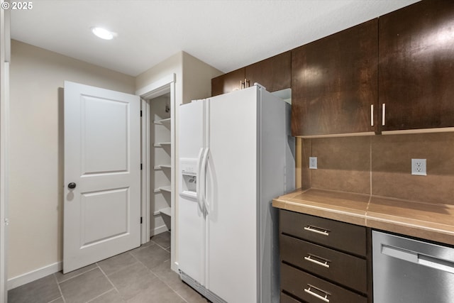 630 NE Adwick Dr, Hillsboro, OR 97006 - kitchen featuring white fridge with ice dispenser, stainless steel dishwasher, dark brown cabinets, and light tile patterned floors