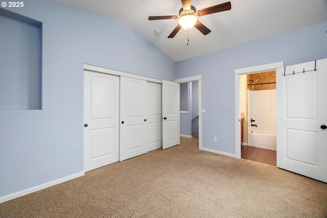 unfurnished bedroom featuring lofted ceiling, connected bathroom, carpet flooring, a closet, and ceiling fan