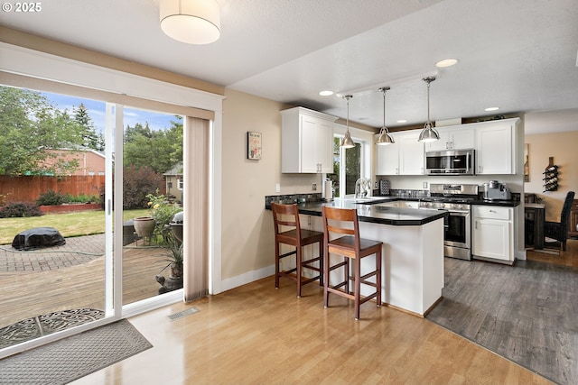 16506 NE 13th St, Vancouver, WA 98684 - kitchen with appliances with stainless steel finishes, a peninsula, light wood finished floors, dark countertops, and white cabinetry