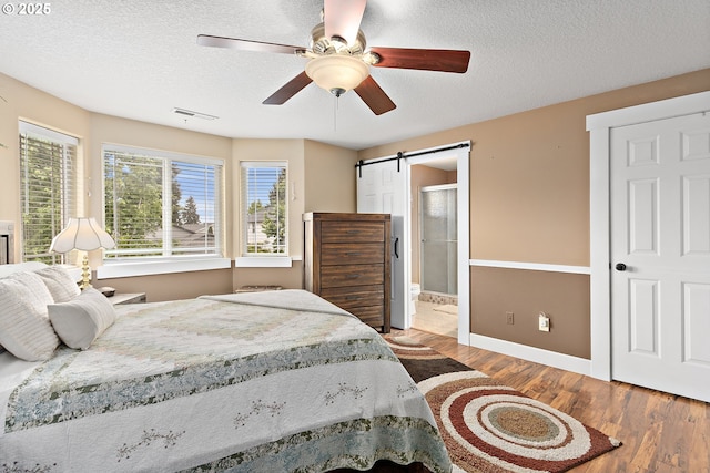 16506 NE 13th St, Vancouver, WA 98684 - bedroom with wood finished floors, a barn door, a textured ceiling, connected bathroom, and ceiling fan