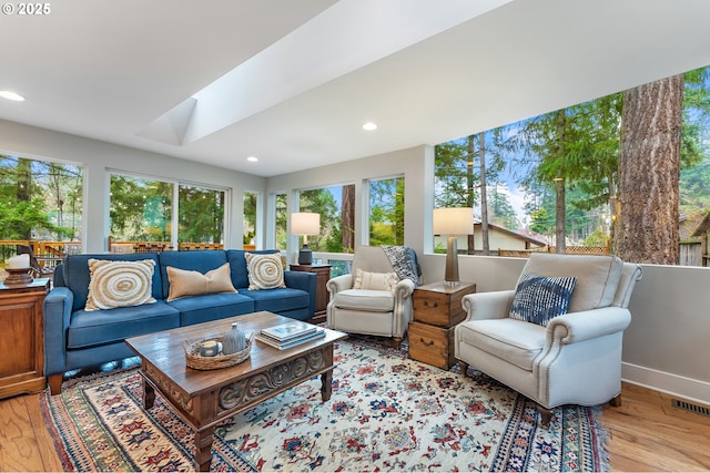 living area with visible vents, baseboards, a skylight, recessed lighting, and light wood-type flooring