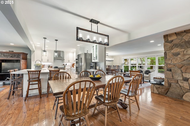 dining area featuring recessed lighting, light wood-style flooring, and a fireplace