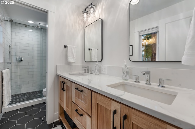 bathroom featuring tile patterned flooring, toilet, a stall shower, and a sink