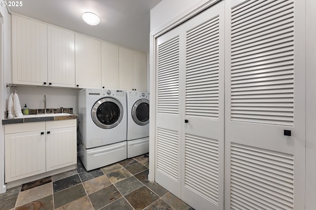 laundry room with a sink, cabinet space, independent washer and dryer, and stone tile flooring