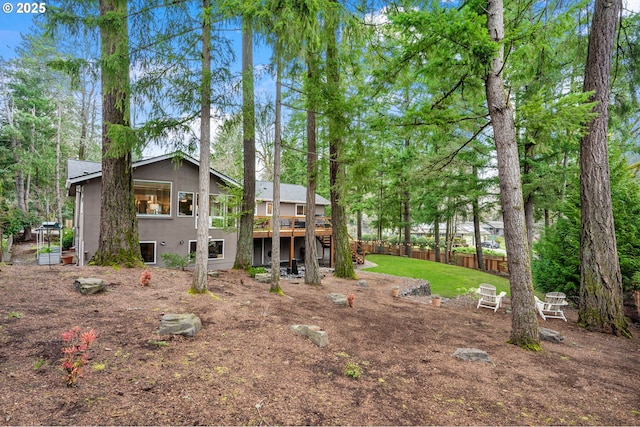 rear view of property with a wooden deck, stucco siding, and fence