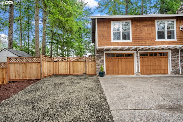 garage featuring a gate, fence, and driveway