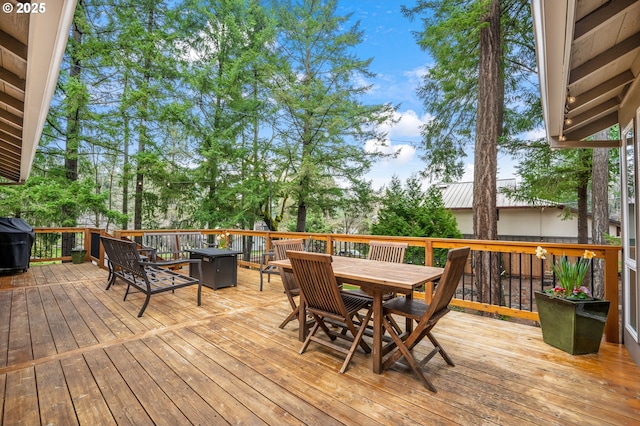 wooden terrace featuring outdoor dining area and a grill