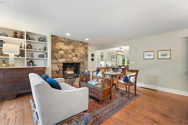 living area with recessed lighting, baseboards, wood finished floors, and a fireplace