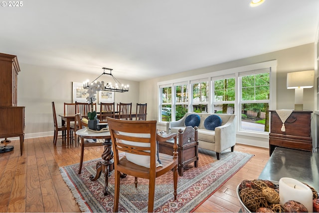 dining room with baseboards, a notable chandelier, and light wood-style flooring