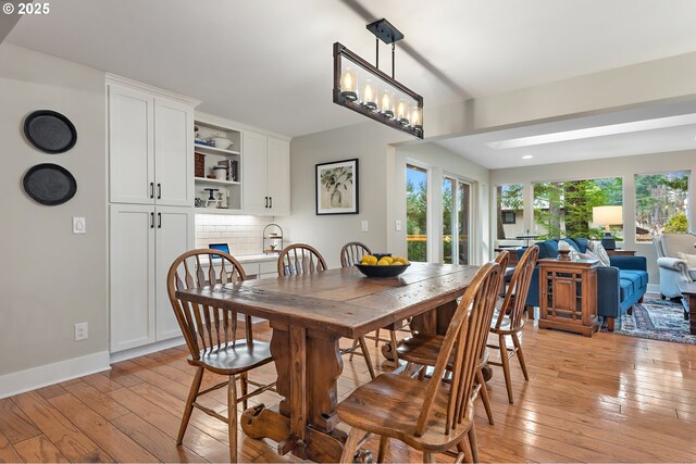 dining space with a wealth of natural light, light wood-type flooring, and baseboards