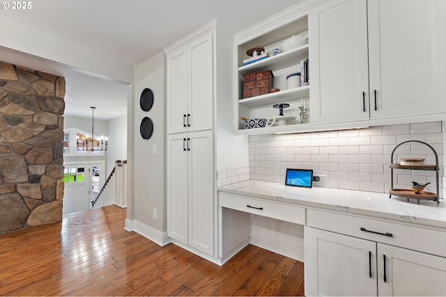 kitchen featuring light wood-type flooring, open shelves, light stone counters, backsplash, and white cabinetry