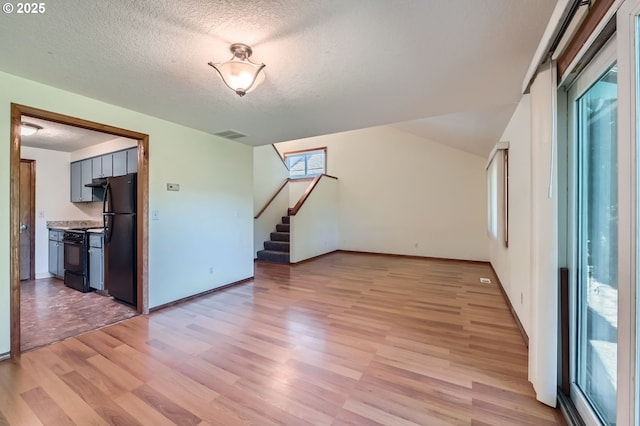 121 SE 34th Cir, Troutdale, OR 97060 - unfurnished living room featuring light wood-type flooring, a textured ceiling, and stairs