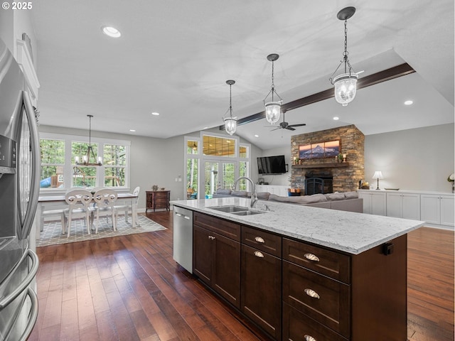 kitchen with dark wood finished floors, vaulted ceiling, ceiling fan with notable chandelier, a fireplace, and stainless steel appliances