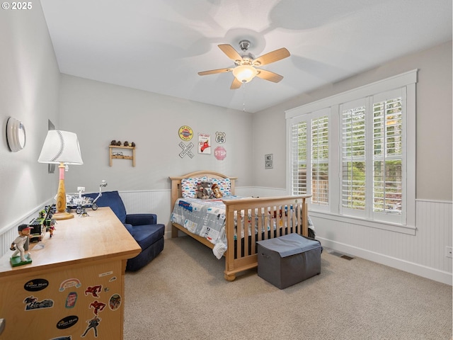 bedroom with visible vents, wainscoting, ceiling fan, and carpet floors