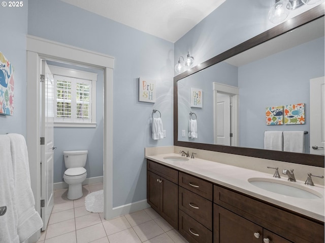 bathroom featuring a sink, toilet, double vanity, and tile patterned floors
