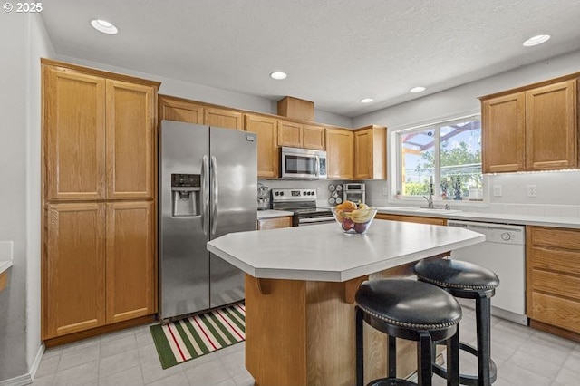 1227 Trent Ave, Keizer, OR 97303 - kitchen featuring appliances with stainless steel finishes, light countertops, a breakfast bar area, a kitchen island, and recessed lighting