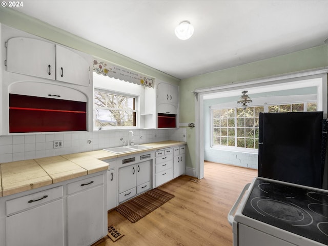 kitchen with sink, black fridge, tile countertops, white electric stove, and white cabinets