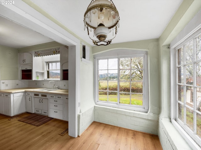 kitchen with sink, a wealth of natural light, white cabinets, and light hardwood / wood-style flooring