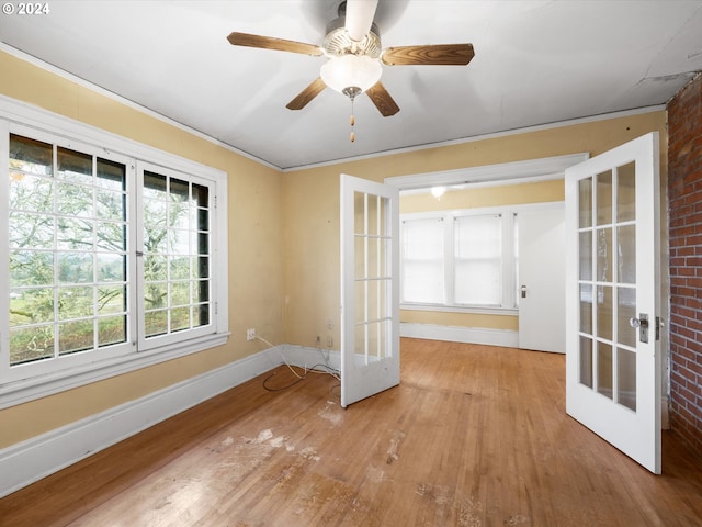 empty room with ceiling fan, ornamental molding, light hardwood / wood-style floors, brick wall, and french doors