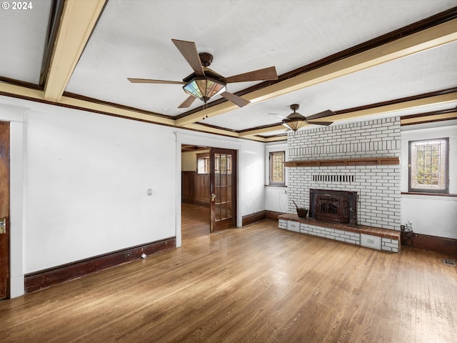 unfurnished living room with crown molding, hardwood / wood-style flooring, ceiling fan, a brick fireplace, and beamed ceiling