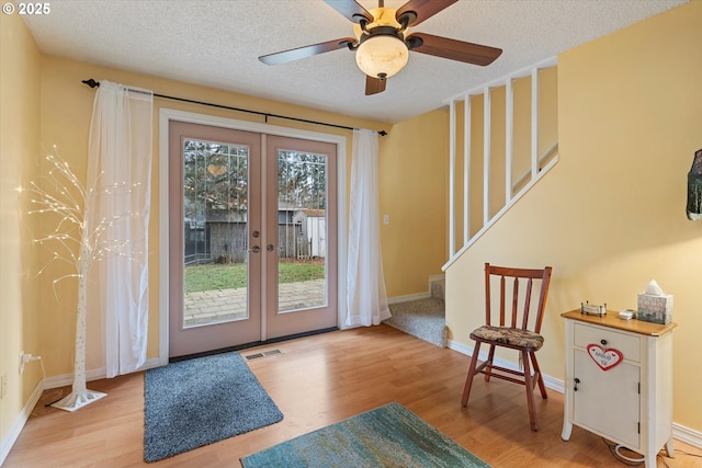 doorway to outside featuring french doors, ceiling fan, a textured ceiling, and light hardwood / wood-style flooring