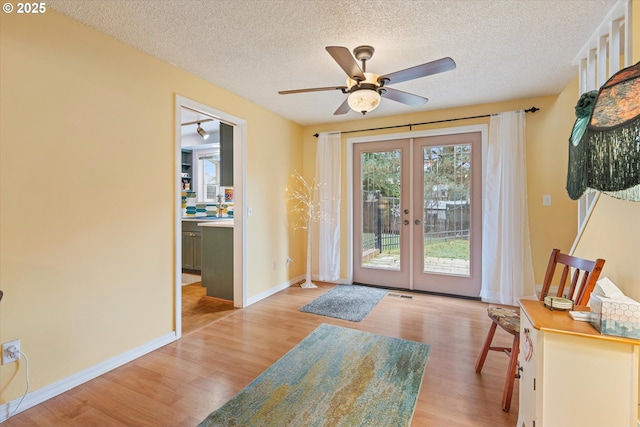 entryway with french doors, ceiling fan, a textured ceiling, and light wood-type flooring