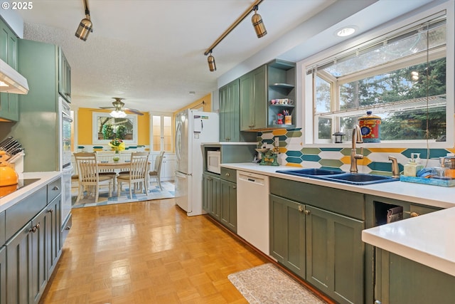 kitchen featuring tasteful backsplash, sink, green cabinets, and white appliances