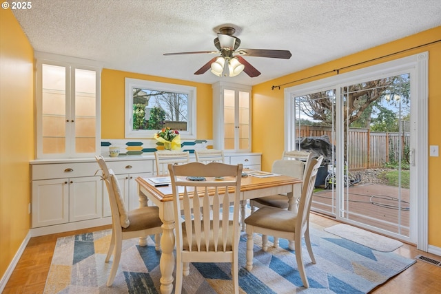 dining space with light parquet floors, ceiling fan, and a textured ceiling