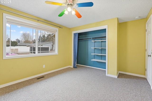 unfurnished bedroom with ceiling fan, a closet, carpet flooring, and a textured ceiling