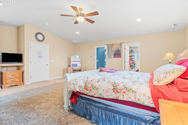 carpeted bedroom featuring ceiling fan, vaulted ceiling, and a walk in closet