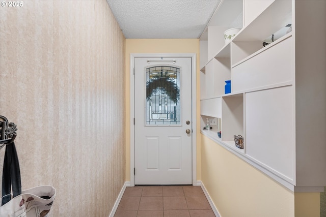 doorway to outside featuring light tile patterned flooring and a textured ceiling