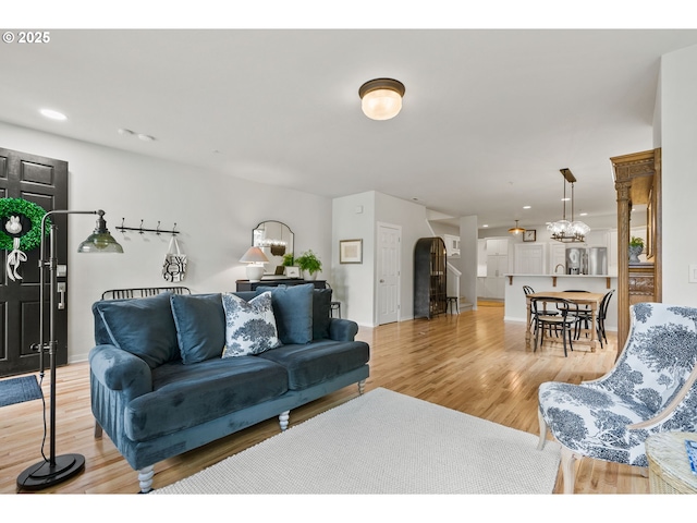 living room featuring arched walkways, baseboards, a notable chandelier, and light wood finished floors