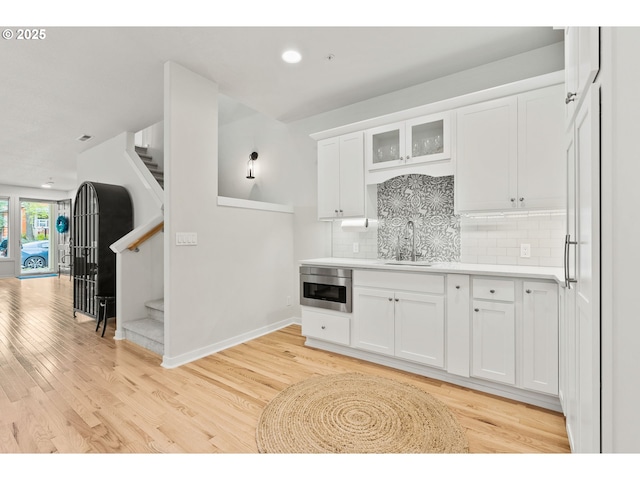 kitchen with light wood-style floors, a sink, and white cabinetry