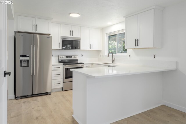 2817 Applewood Ln, Eugene, OR 97408 - kitchen with appliances with stainless steel finishes, a peninsula, light wood finished floors, white cabinets, and light countertops