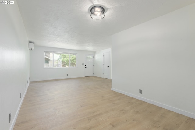 2817 Applewood Ln, Eugene, OR 97408 - spare room with a wall mounted air conditioner, light wood-style floors, and a textured ceiling