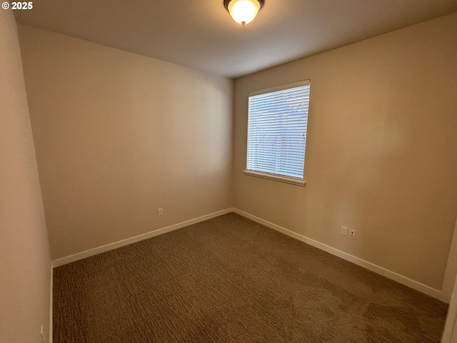 spare room featuring dark colored carpet