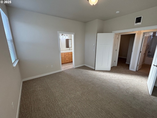 unfurnished bedroom with ensuite bath and light carpet