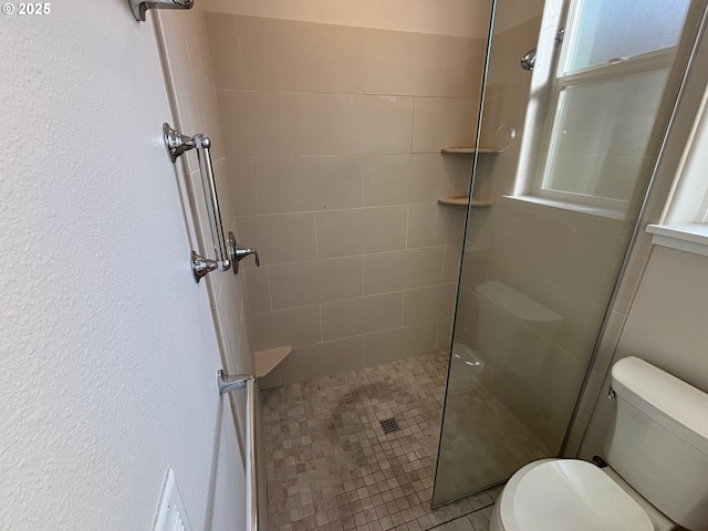 bathroom featuring toilet, tile patterned flooring, a wealth of natural light, and a shower with shower door