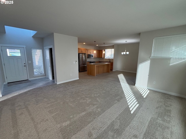 unfurnished living room with light colored carpet, sink, and a notable chandelier