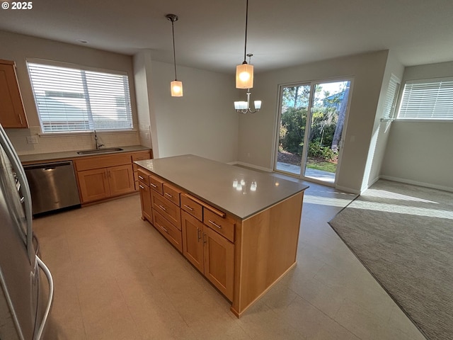 kitchen featuring an inviting chandelier, stainless steel appliances, a kitchen island, pendant lighting, and sink