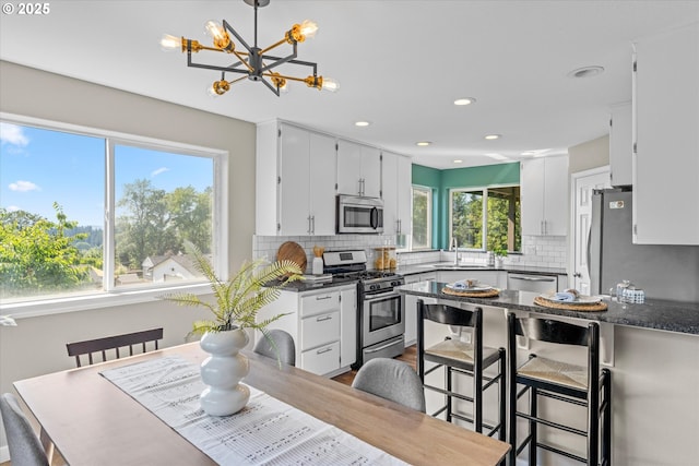 6902 SW Taylors Ferry Rd, Portland, OR 97223 - kitchen featuring appliances with stainless steel finishes, a chandelier, backsplash, white cabinetry, and recessed lighting
