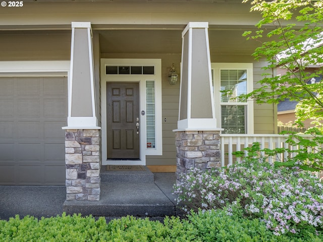 180 N The Greens Ave, Newberg, OR 97132 - view of exterior entry with stone siding, a porch, and a garage